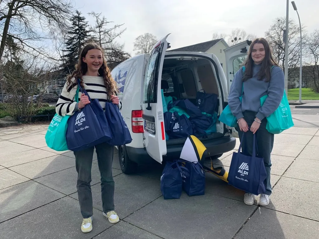 Sophie und Pia mit vollen Spendentaschen vor einem Van der Bonn International School